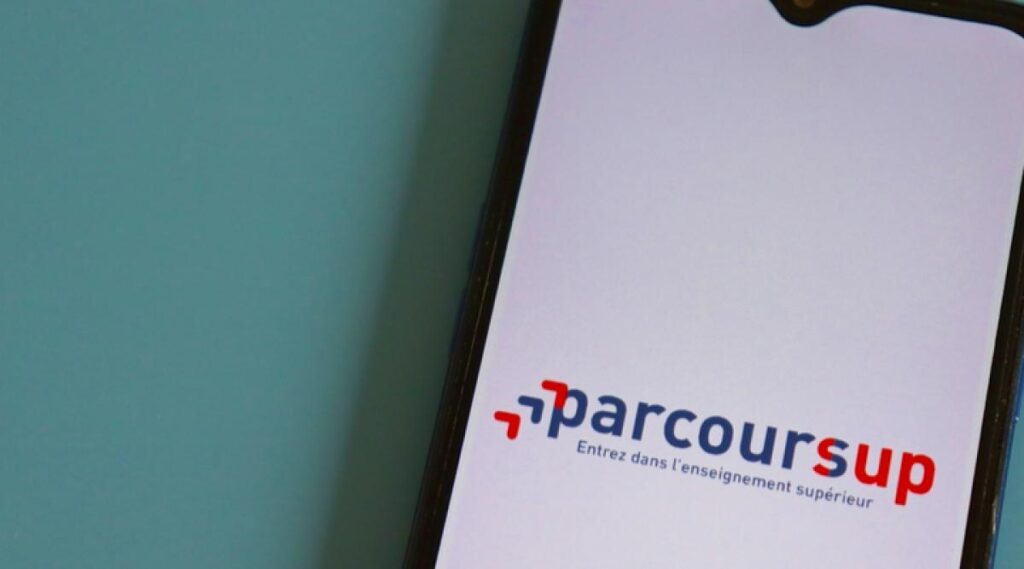Écran de smartphone affichant le logo de la plateforme française Parcoursup, avec le texte "parcoursup" en bleu et rouge, suivi du slogan "Entrez dans l’enseignement supérieur" en dessous. Le fond de l’écran est blanc, et le téléphone est posé sur une surface bleu clair.